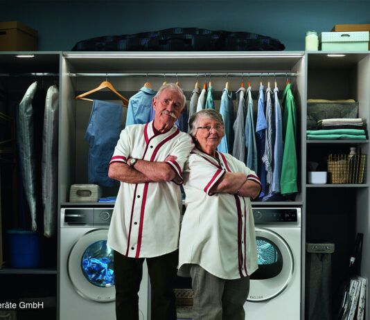 Bosch Hausgeräte kündigt Cashback-Aktion für ausgewählte Geräte ab September 2026 an Ein Mann und eine Frau in hellen Uniformen stehen lächelnd vor zwei Waschmaschinen in einer voll ausgestatteten Waschküche