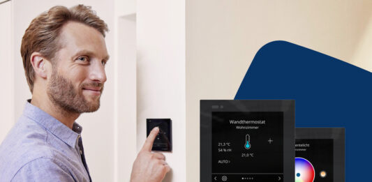 Homematic IP Glasdisplay – plus: Jetzt auch für Funk-Systeme und mit neuen Features Person steht vor einem Homematic-IP-Glasdisplay - plus