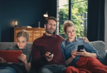 FRITZ!Box: Vodafone bringt Wi-Fi 7 ins Kabelnetz Vater, Mutter und Sohn sitzen auf einem Sofa und nutzen ein Tablet, eine Fernbedienung sowie ein Smartphone