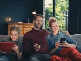 FRITZ!Box: Vodafone bringt Wi-Fi 7 ins Kabelnetz Vater, Mutter und Sohn sitzen auf einem Sofa und nutzen ein Tablet, eine Fernbedienung sowie ein Smartphone