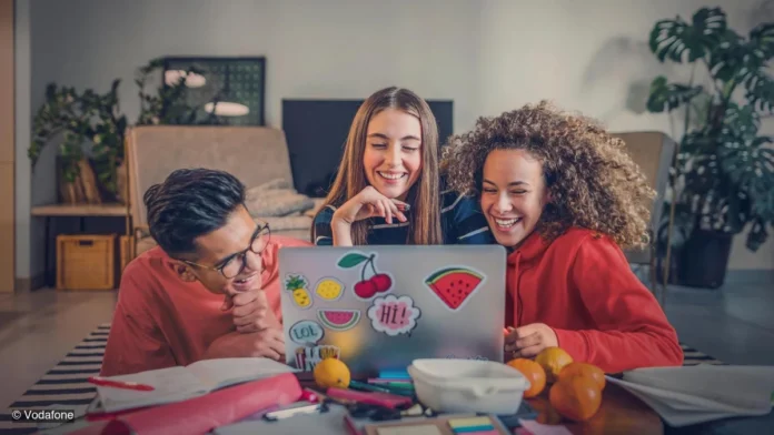 Vodafone-Hausaufgaben-mit-Ki Schüler sitzen vor einem Laptop und lachen